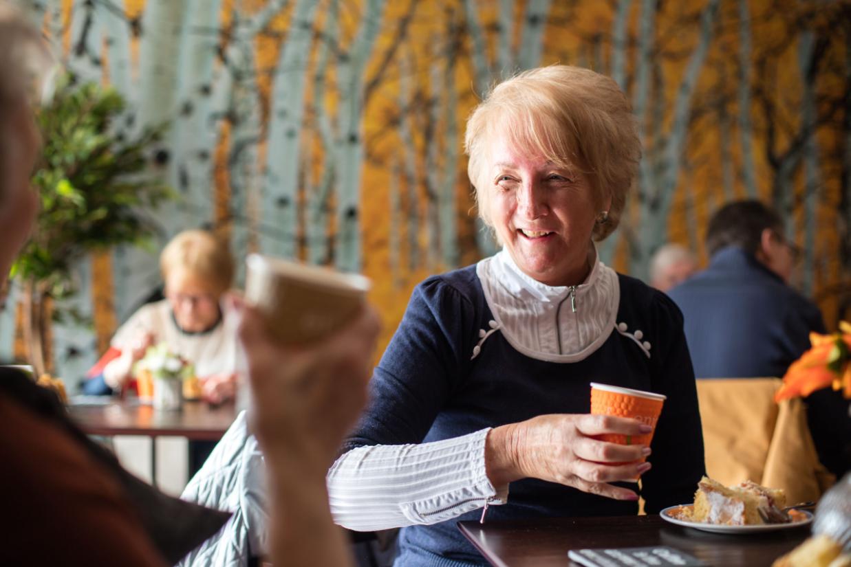 older lady smiling and holding a cup