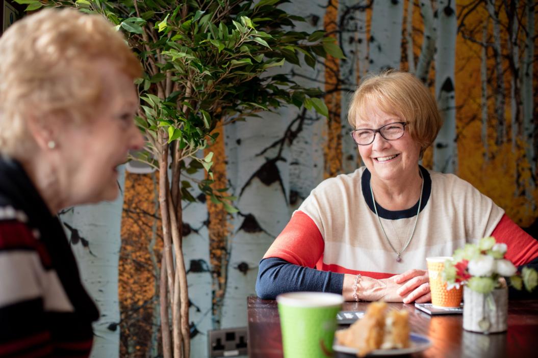 an older lady sat smiling at her friend